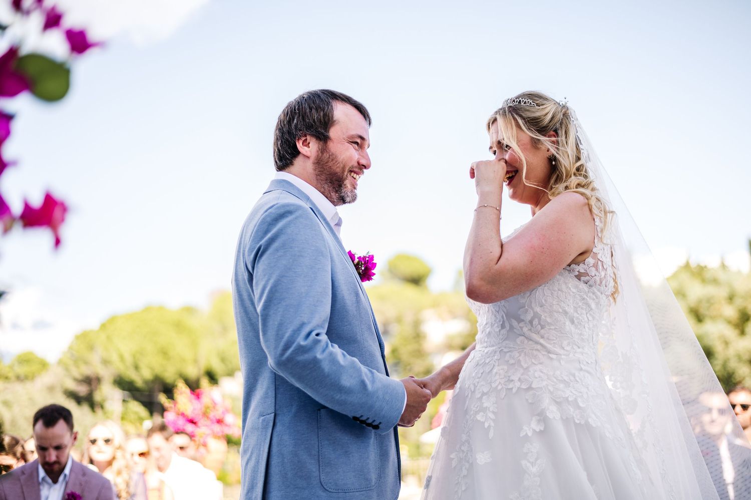 A romantic outdoor wedding ceremony with vibrant pink flowers in the foreground.