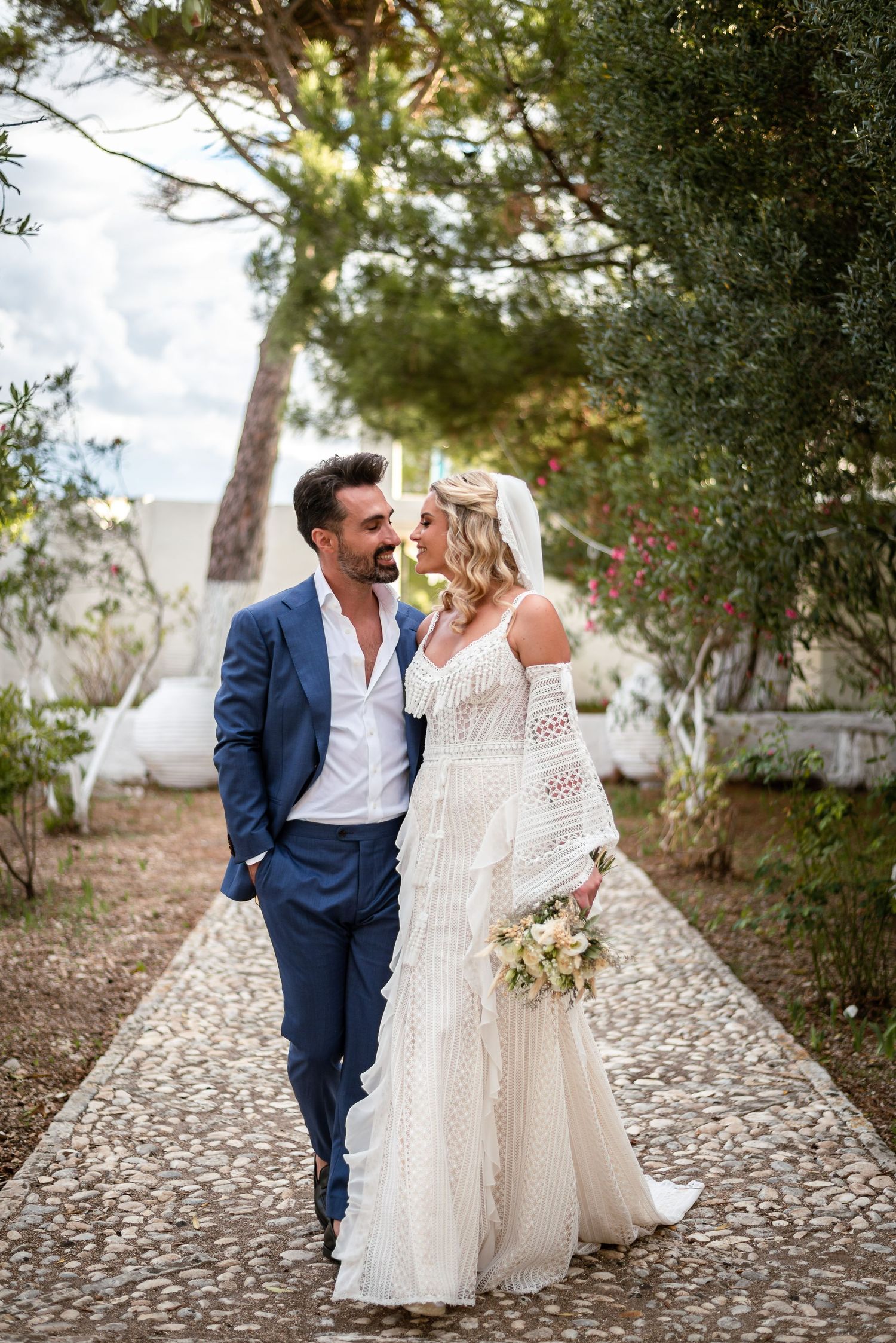 Newlyweds sharing laughter while walking on cobblestone path.