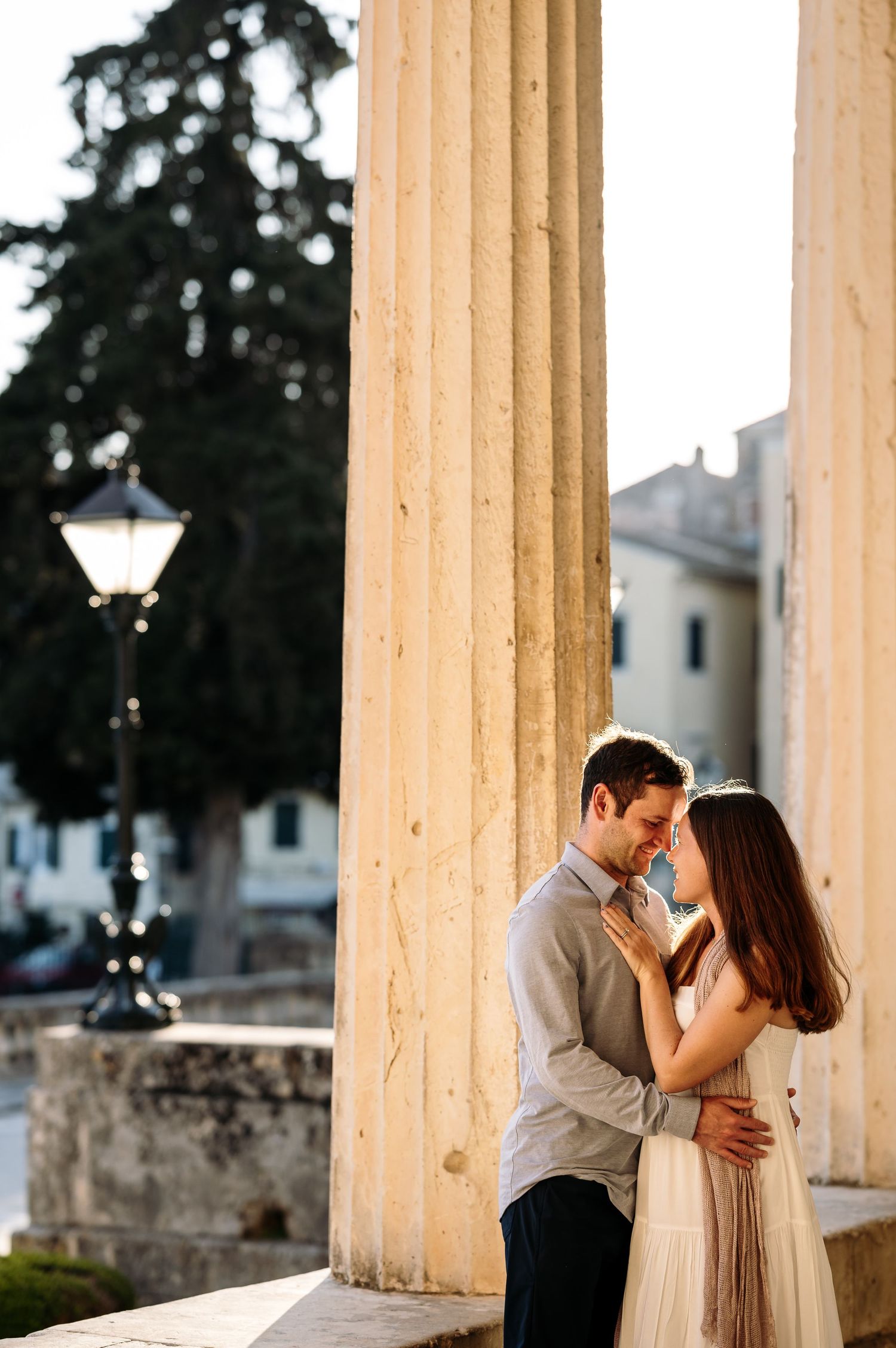 A romantic moment captured between classical stone pillars at golden hour.