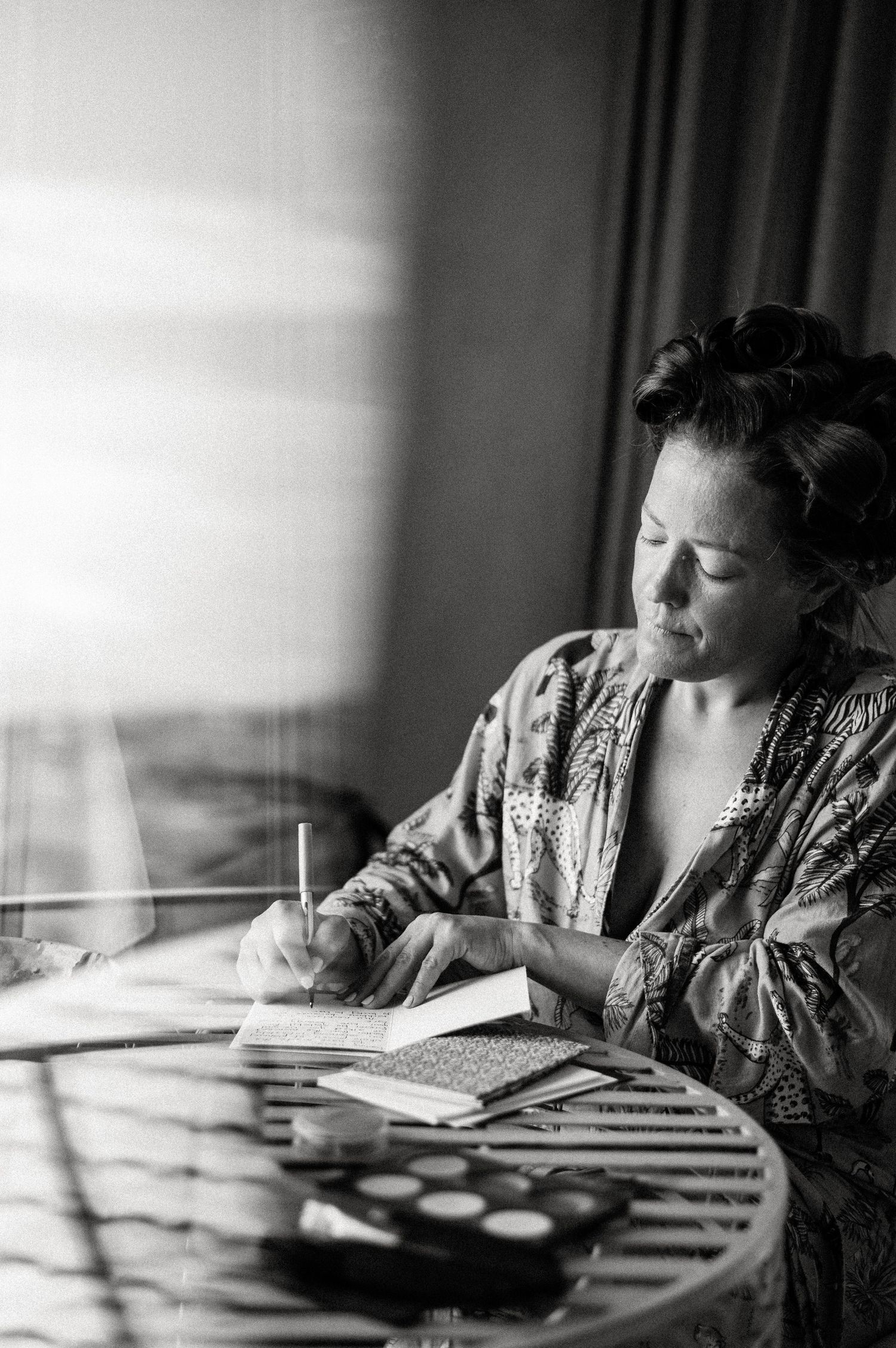Black and white photograph showing a person reading by a window in dramatic lighting.