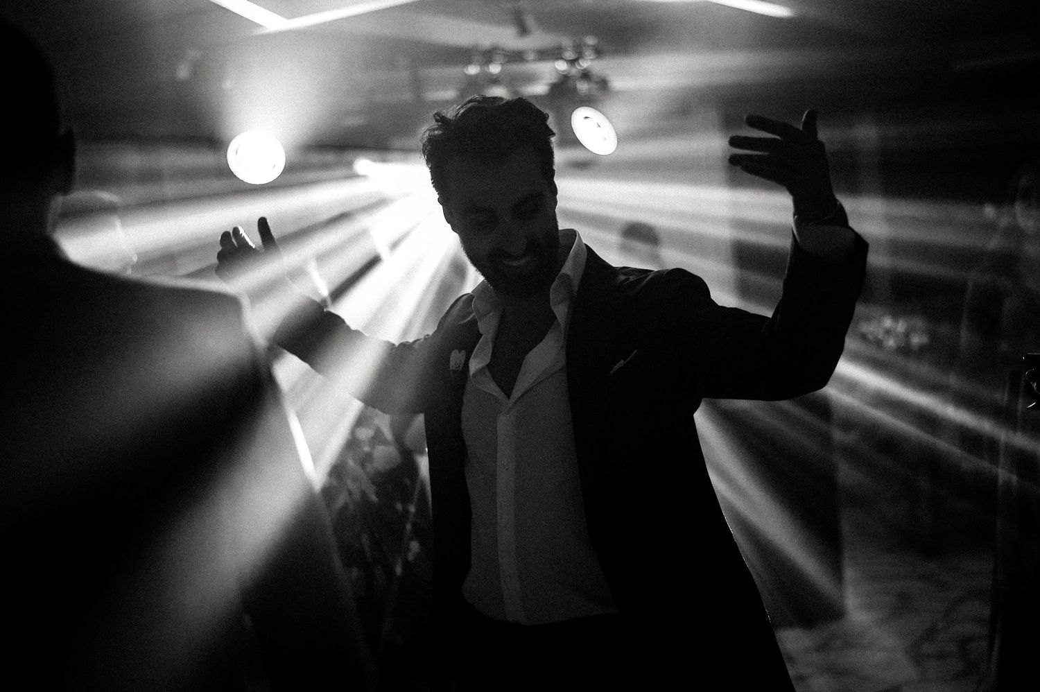Dramatic black and white photo of party silhouettes with bright spotlights.