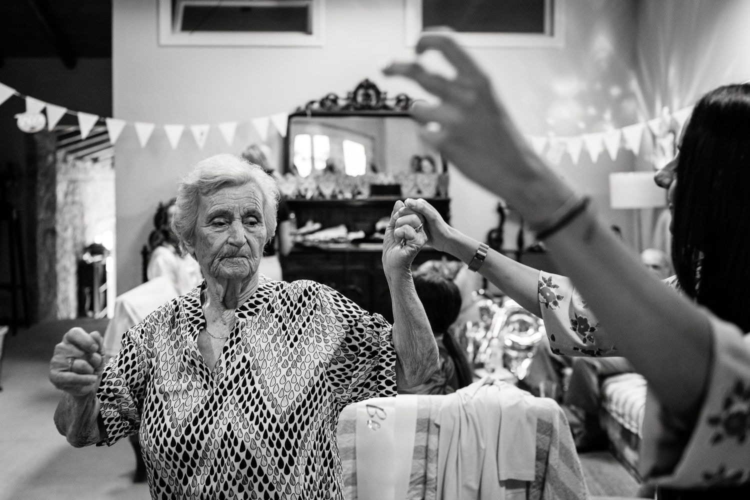 A celebratory indoor gathering with white bunting decorations and festive atmosphere.