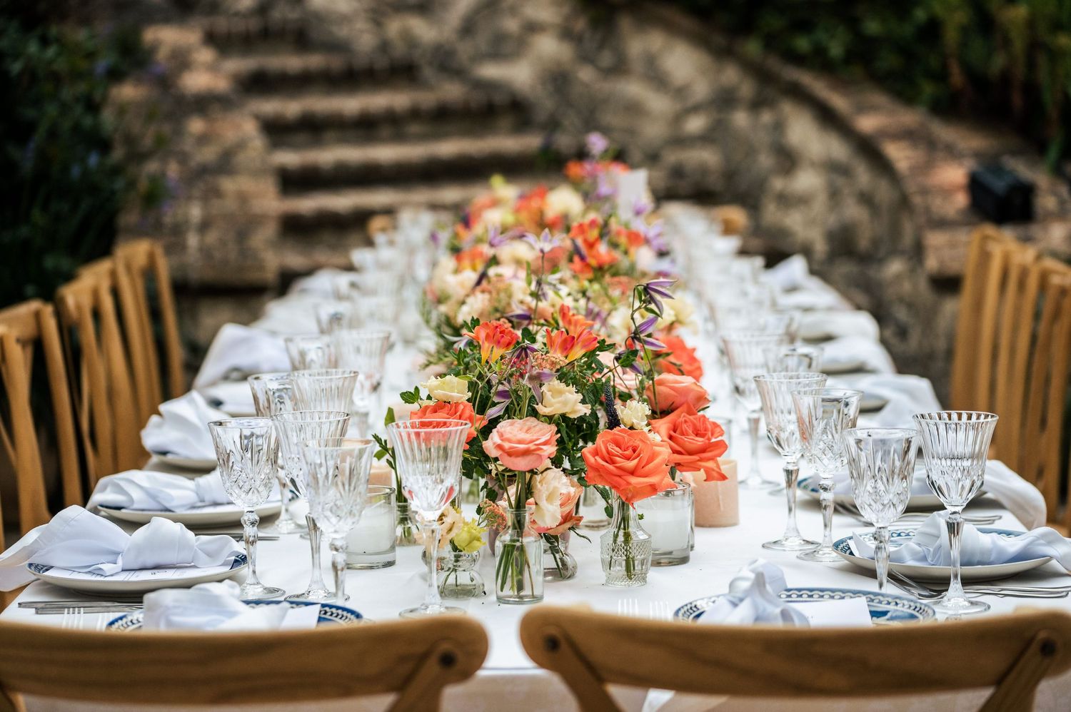 Elegant wedding table setting with coral floral centerpieces and crystal glassware.