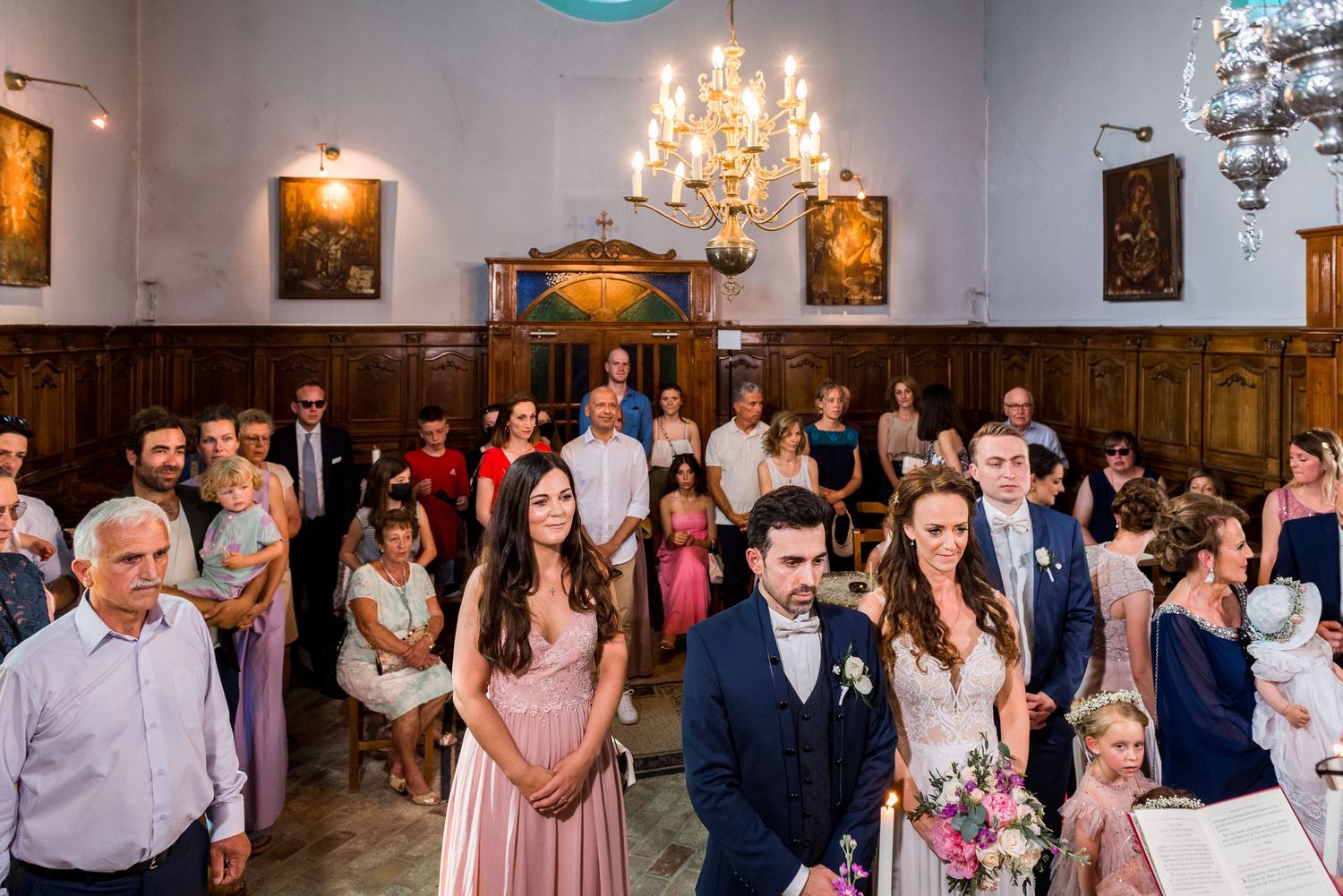 Elegant wedding reception with guests dancing under crystal chandeliers in a historic venue.