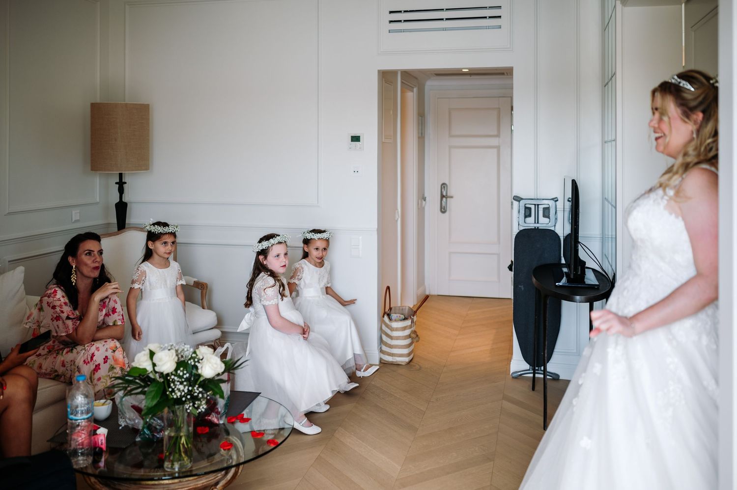 Wedding preparation scene in elegant room with herringbone floors and white walls.
