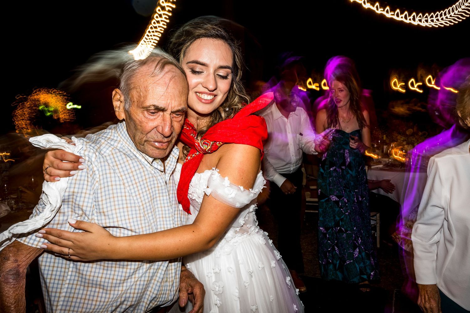 Wedding guests dance in a line formation during reception celebration.