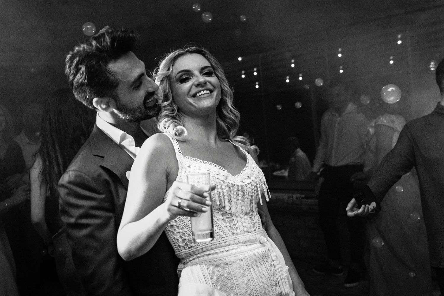 Couples share intimate dance moments under twinkling reception lights.
