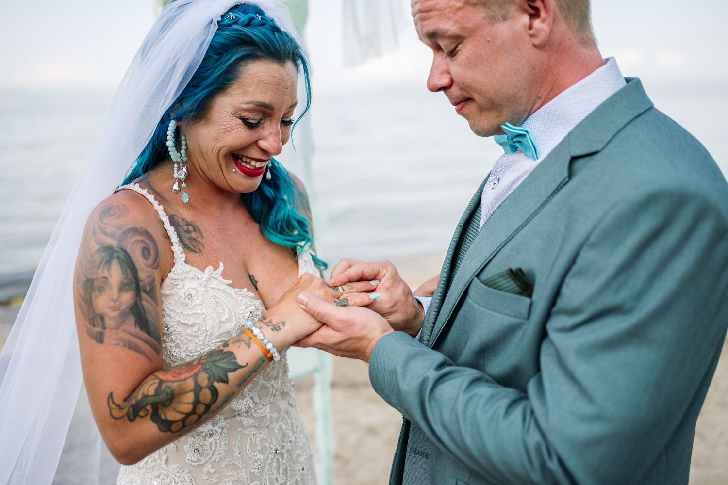 A couple exchanges rings and emotional reactions during a seaside wedding ceremony.