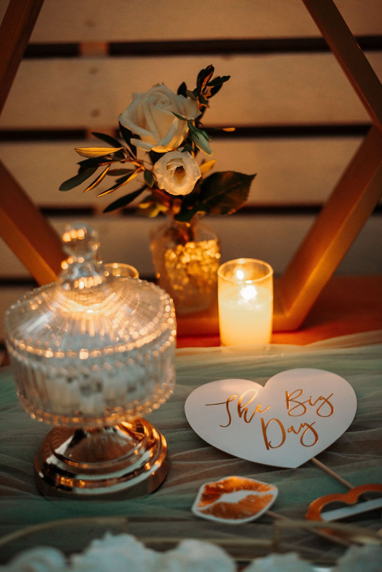 Elegant glass candy dishes with name cards and candles on a teal tablecloth.