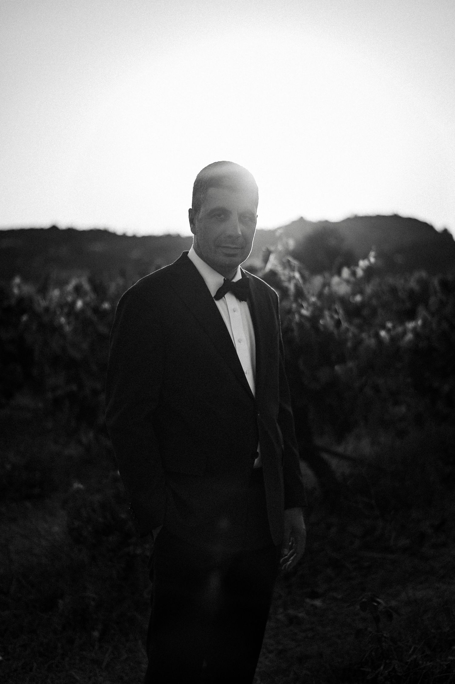 A black and white portrait series of a groom in a vineyard at sunset.