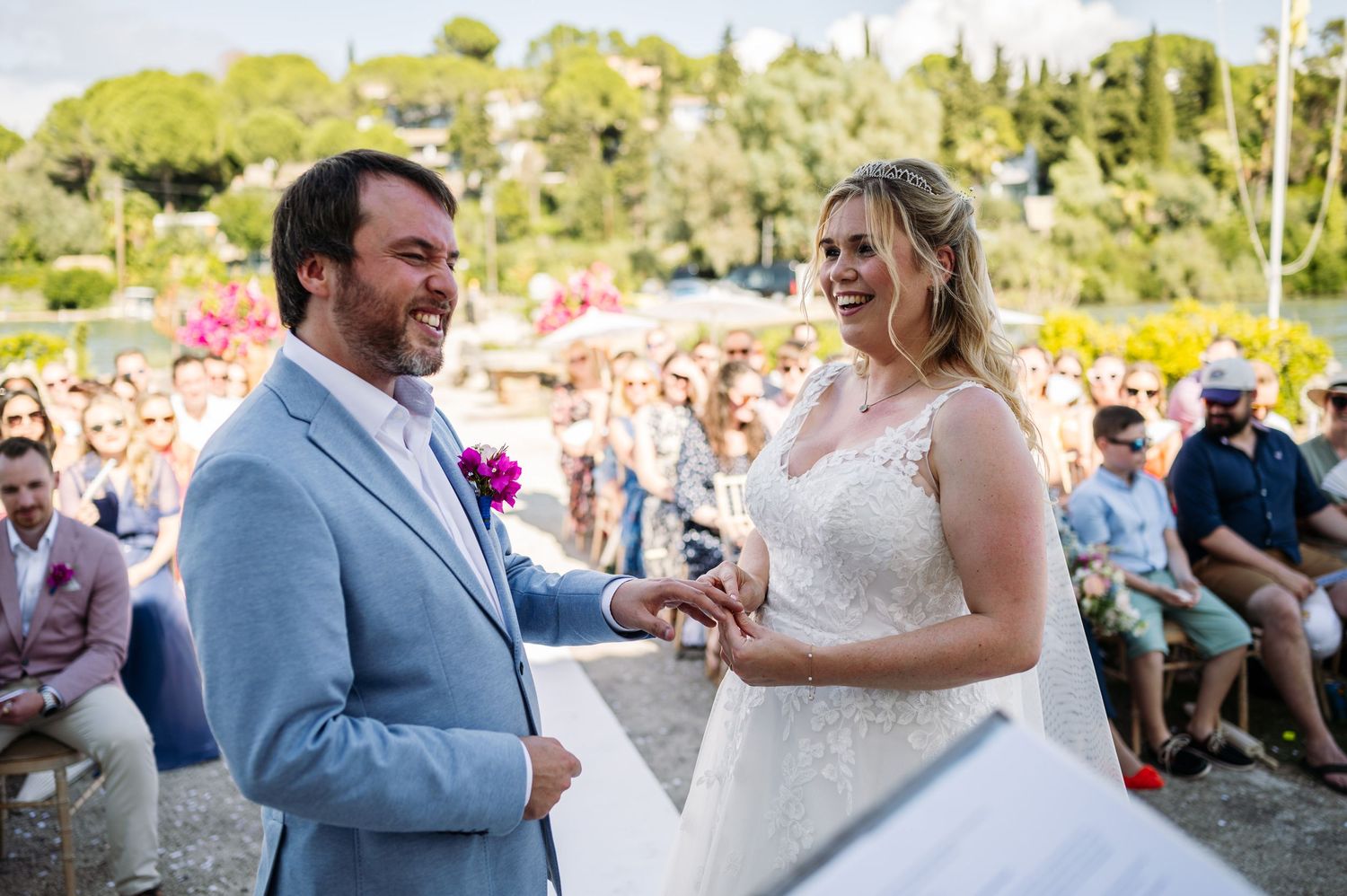 A joyful wedding ceremony moment captured in golden sunlight with guests in the background.