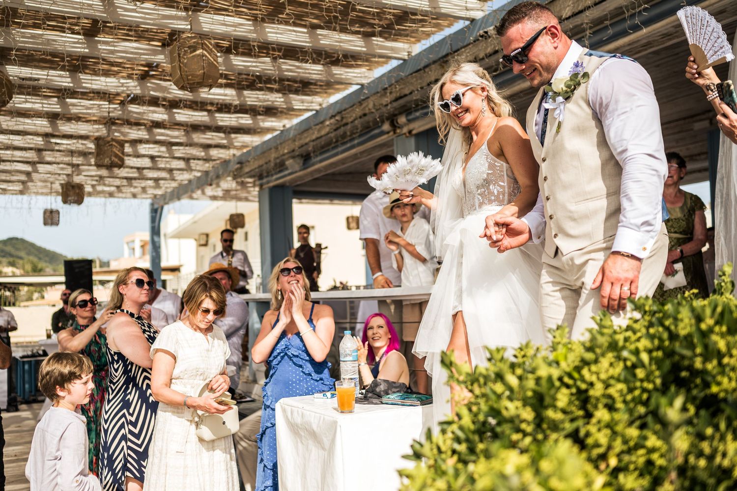 Wedding celebration on a covered terrace with guests watching and cheering.
