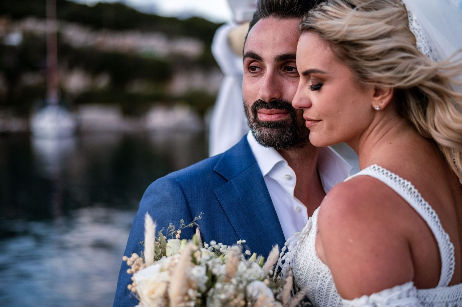 Wedding couple embraces during seaside photo session at sunset.