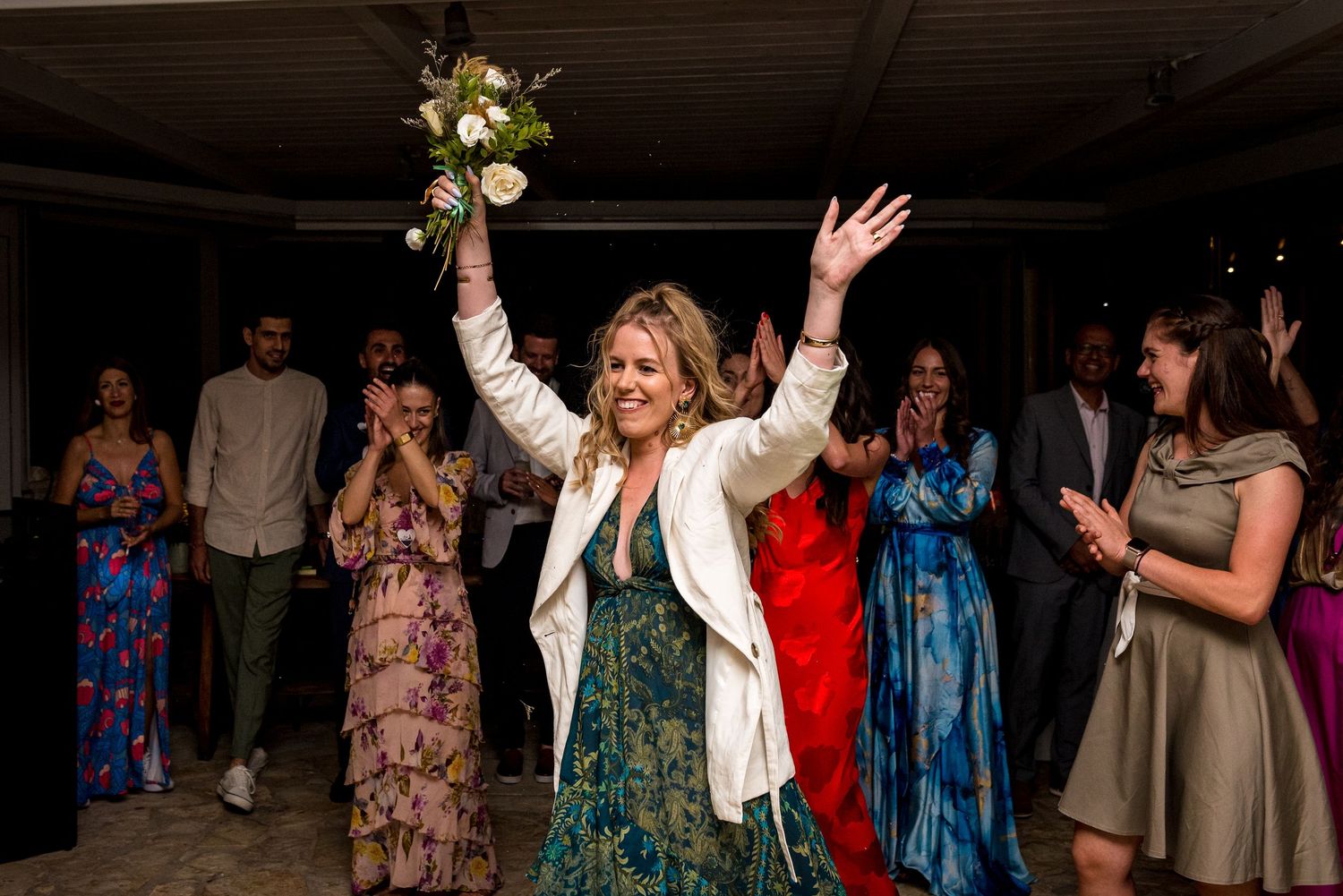 Wedding guests dance and celebrate joyfully on a lively dance floor at an evening reception.