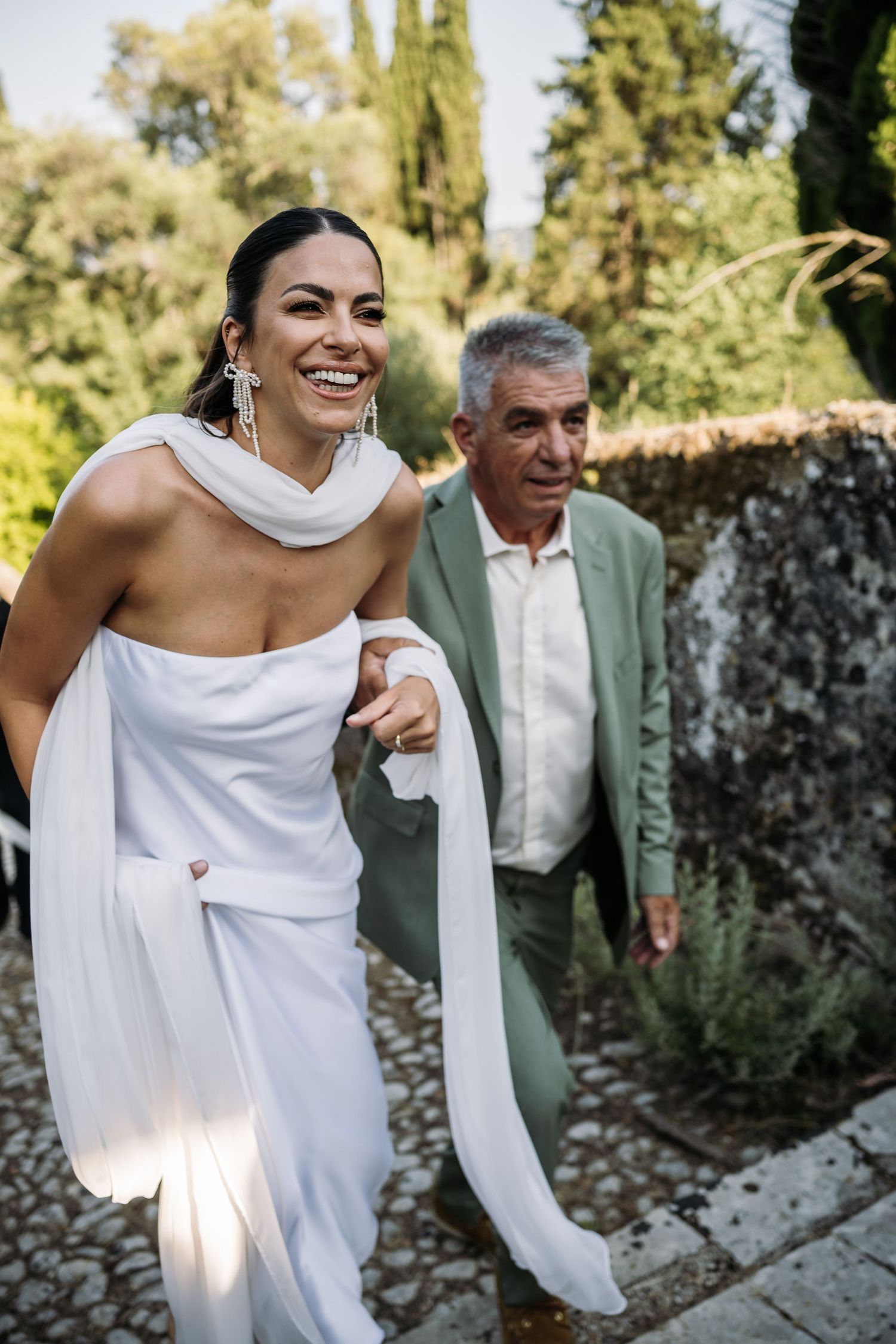 Wedding celebration in a Mediterranean garden with elegant white dress and formal attire.