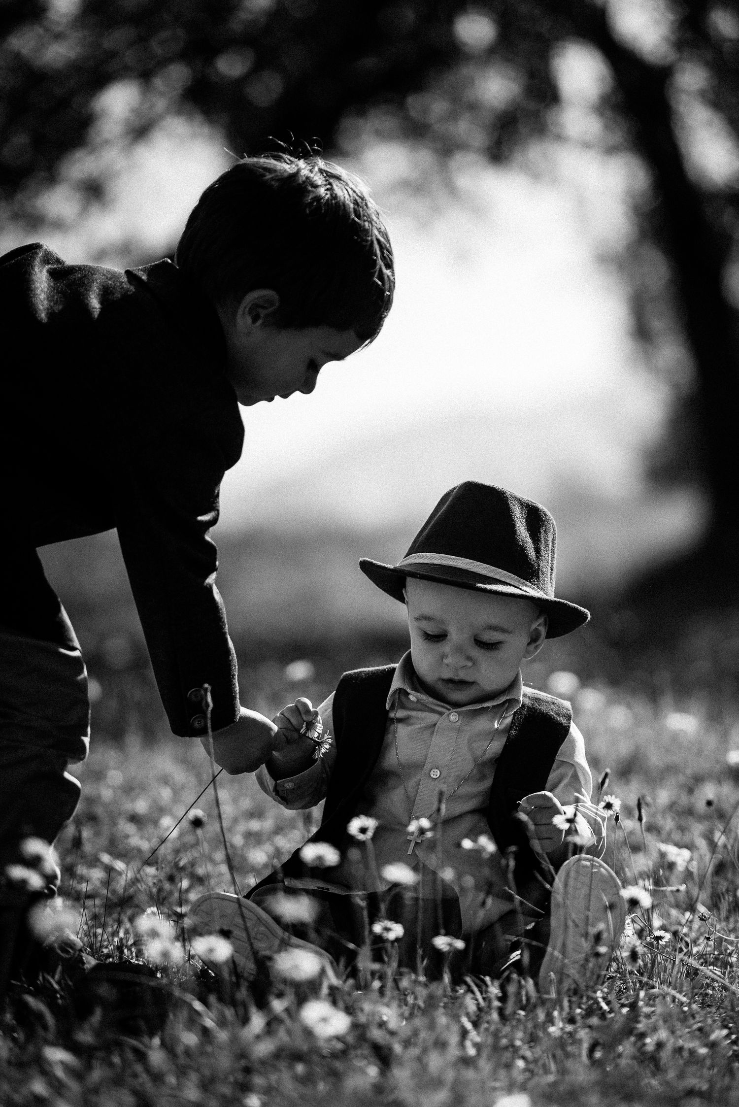 Black and white image of two people examining flowers in a meadow.