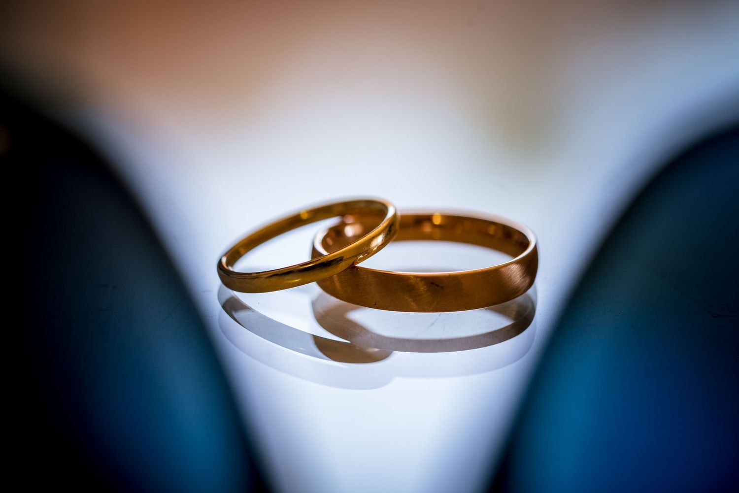 Macro photography of golden wedding rings with dramatic lighting and shallow depth of field.