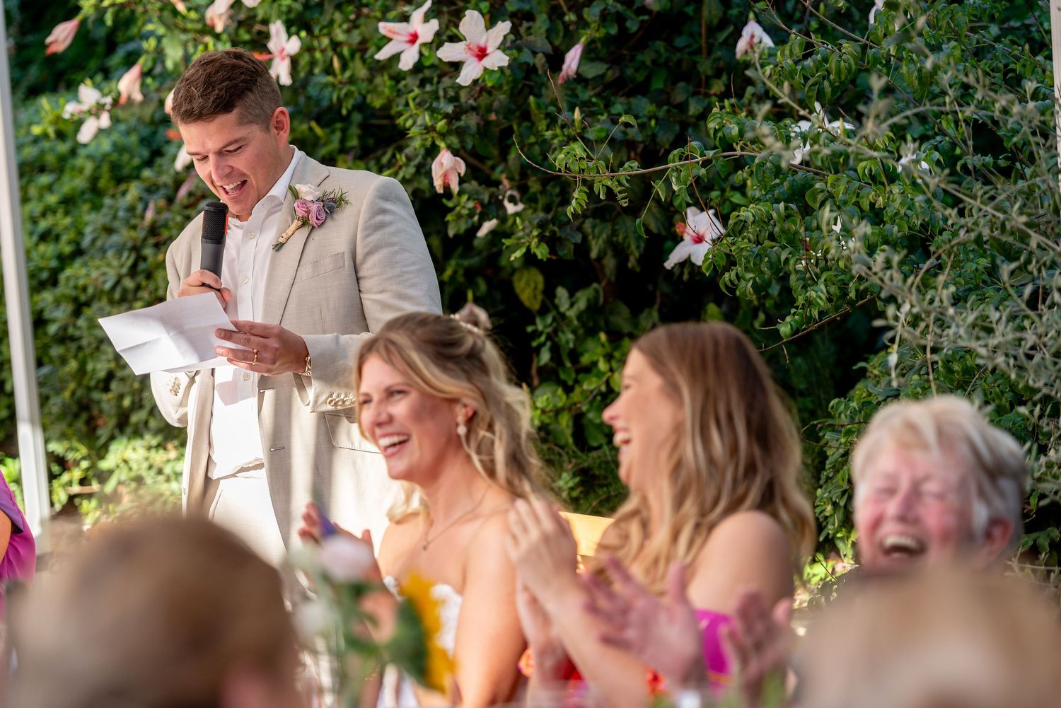 Wedding reception guests seated at decorated tables under outdoor canopy.