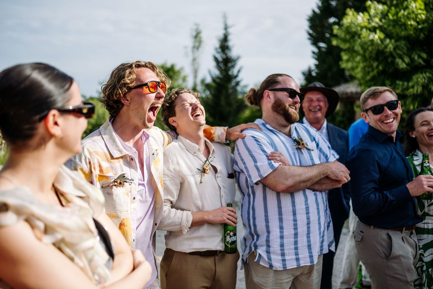 Wedding guests enjoy an outdoor celebration under sunny skies.