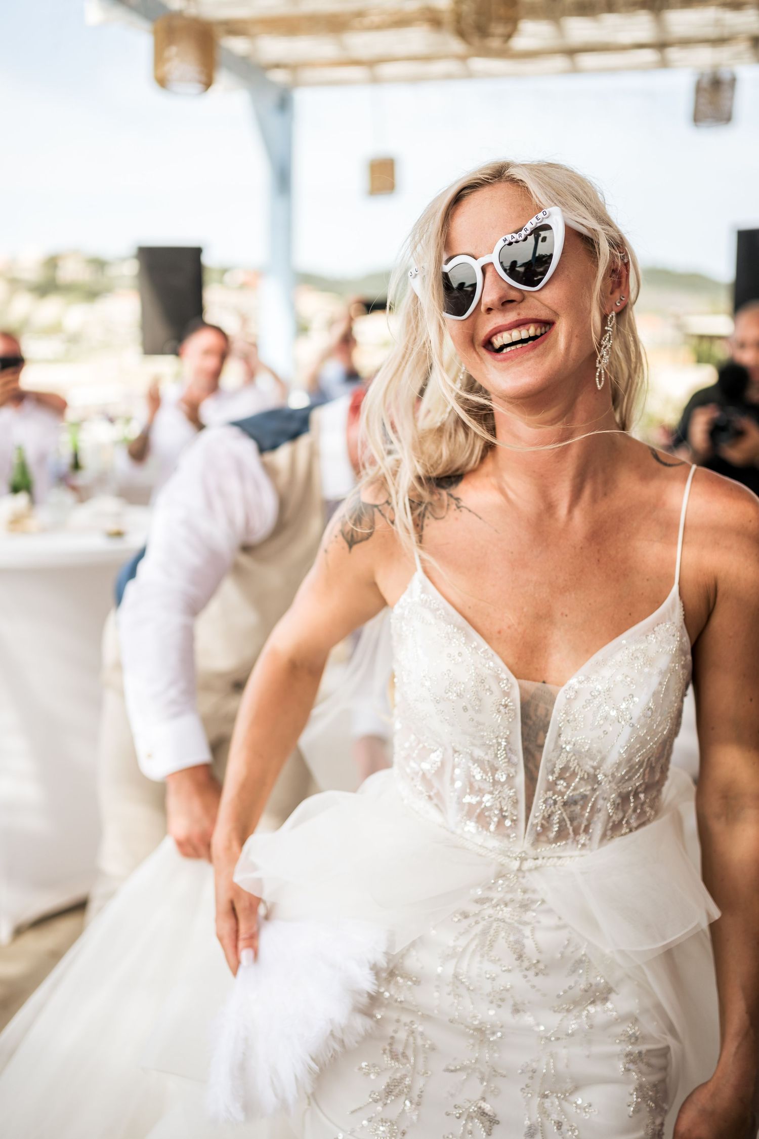 A joyful celebration at a beach wedding with guests dancing and laughing in a covered outdoor venue.