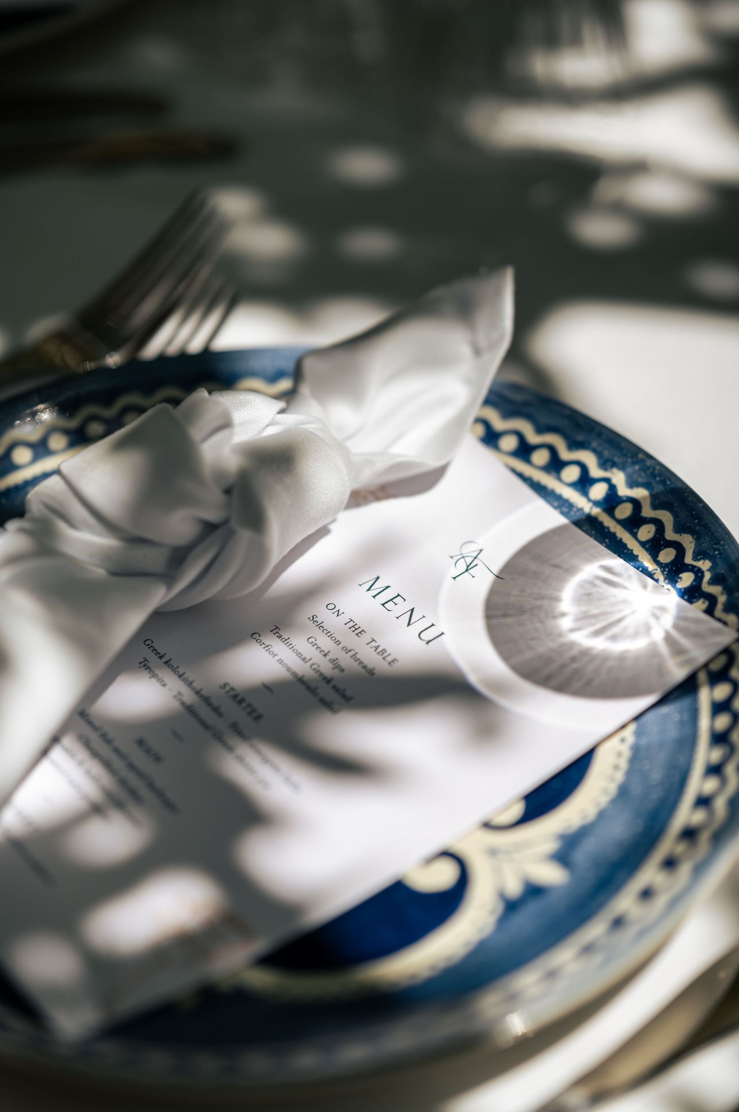 Elegant place settings with blue and white china plates and menu cards on a formal dining table.
