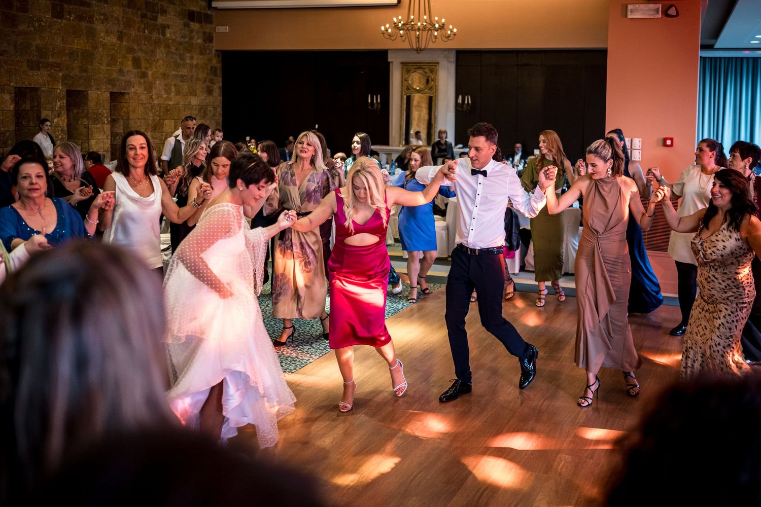 Wedding guests dancing together on a spacious dance floor during lively reception celebration.