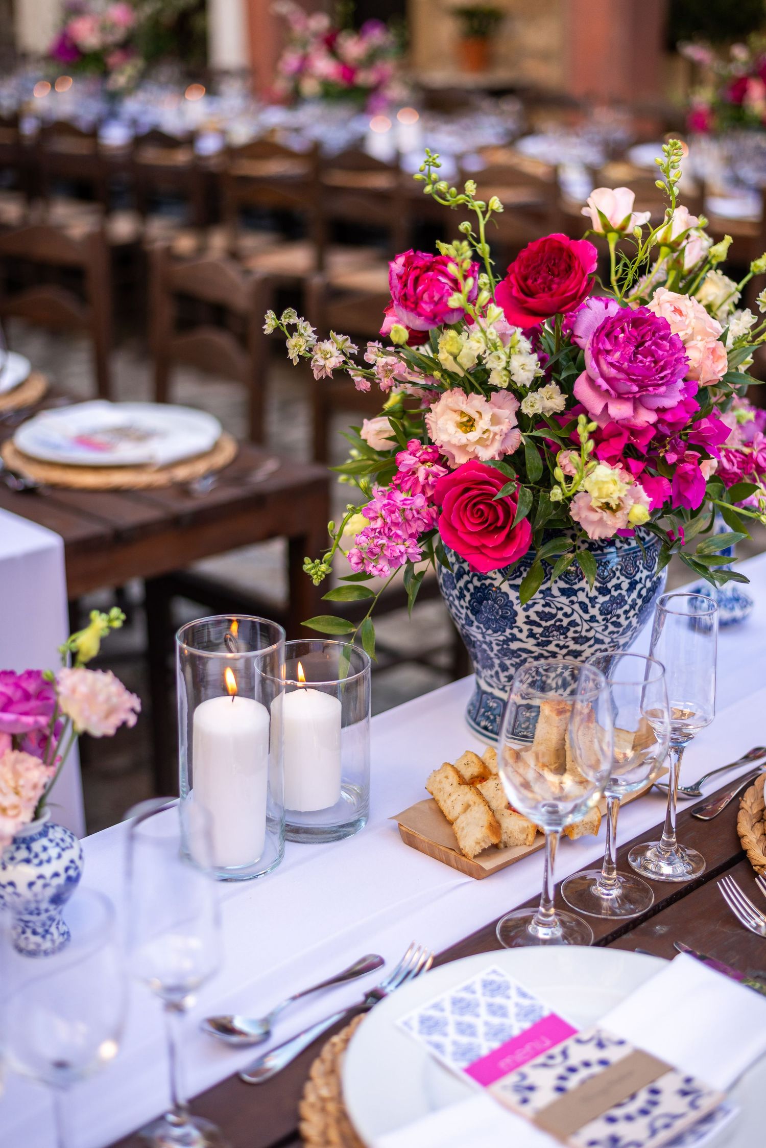 Wedding table decorated with pink and fuchsia flowers in blue and white porcelain vases.