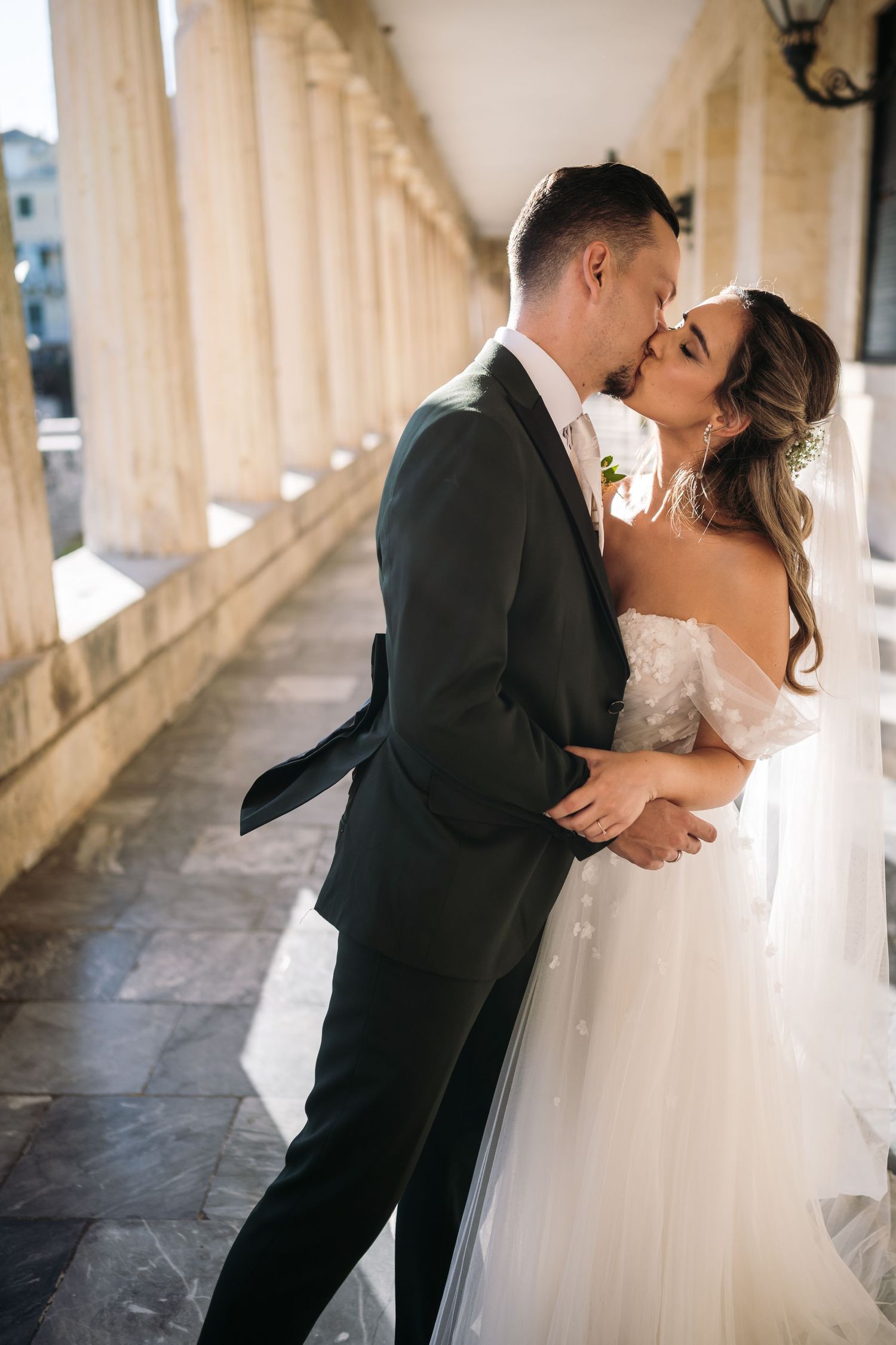 Romantic couple embraces in an elegant colonnade with beautiful natural lighting.