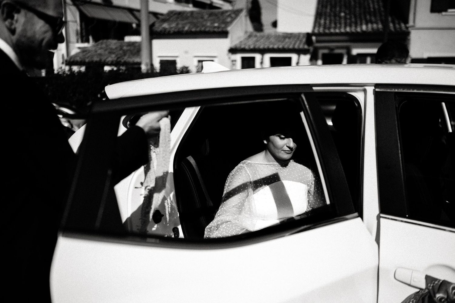 Black and white photo of wedding guests arriving at a venue in vintage cars.