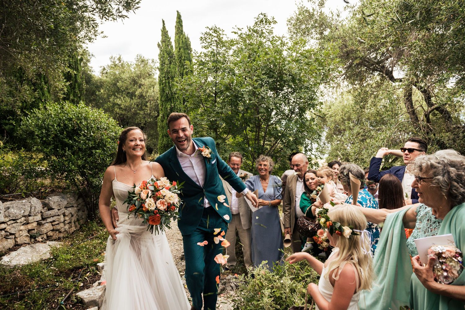 Wedding celebration with guests in pastel attire amid garden landscaping.