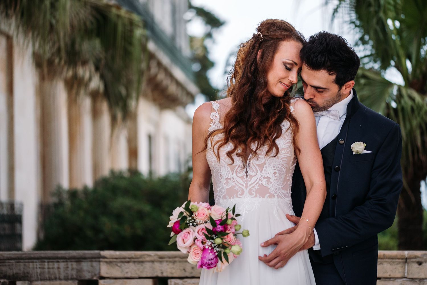 Romantic moments captured in garden setting with classical architecture.