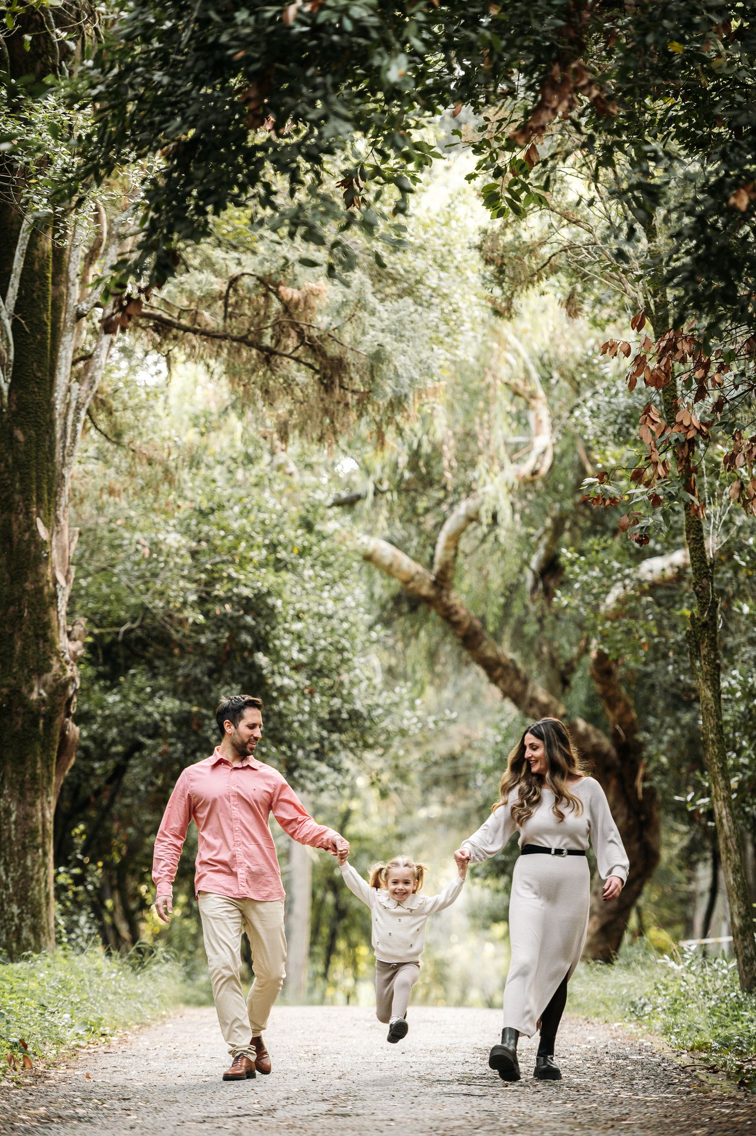 Family enjoying a playful walk together on a tree-lined nature path.