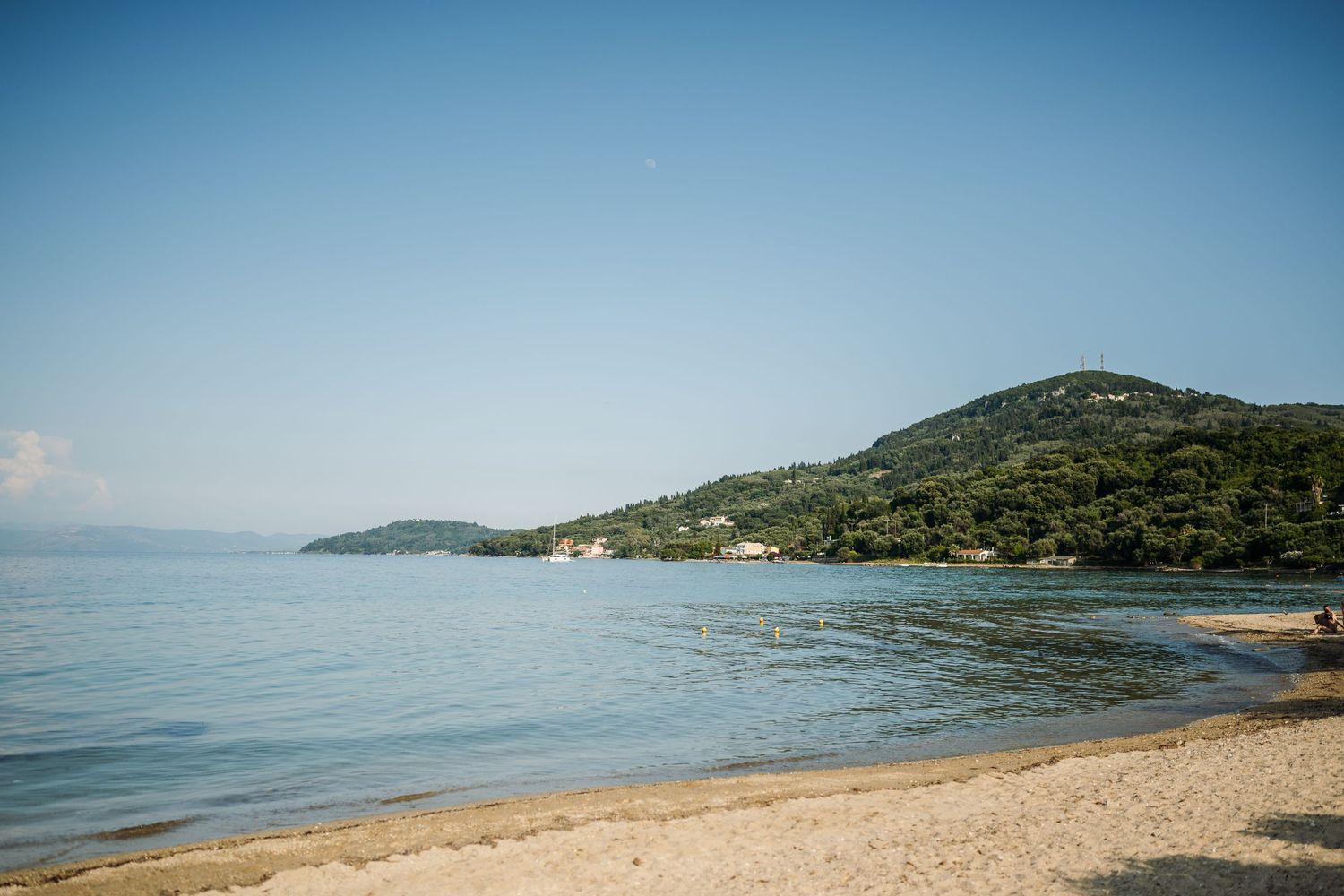 Panoramic view of a coastal landscape with blue waters and green hills.