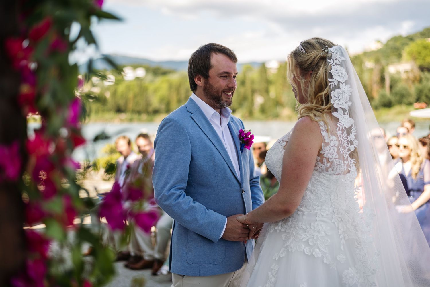 Outdoor wedding ceremony with bright pink bougainvillea flowers in foreground.