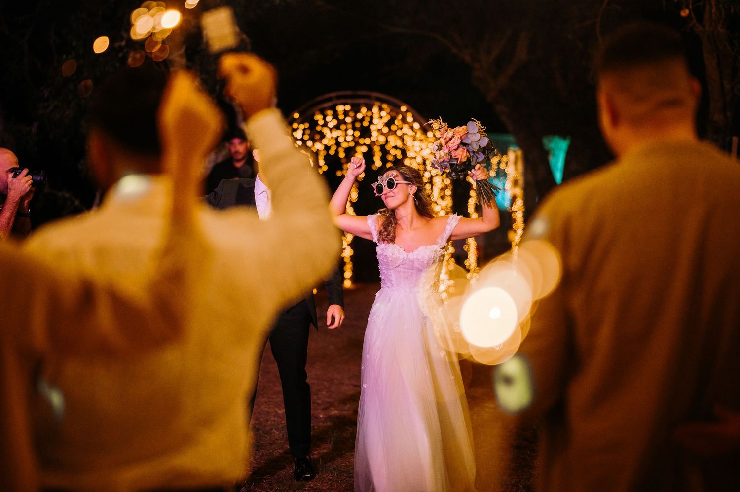 Atmospheric nighttime wedding reception with warm lighting and dancing silhouettes.