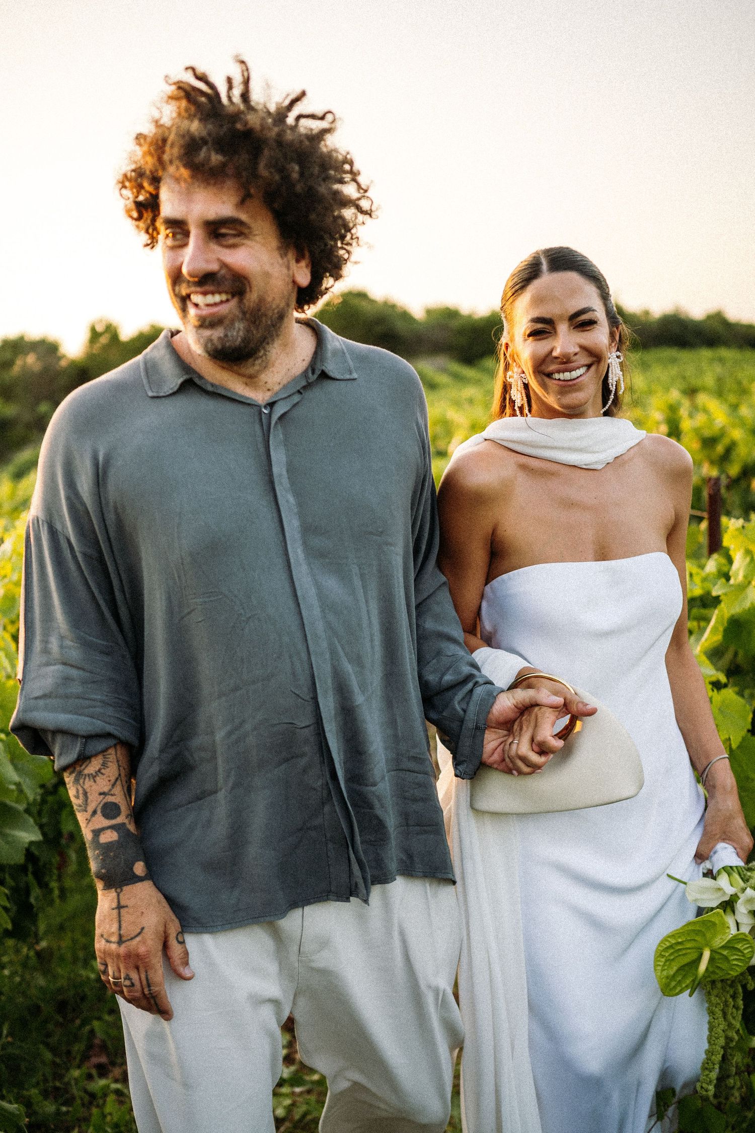 Couple in casual attire enjoying a romantic moment in a sunlit vineyard.