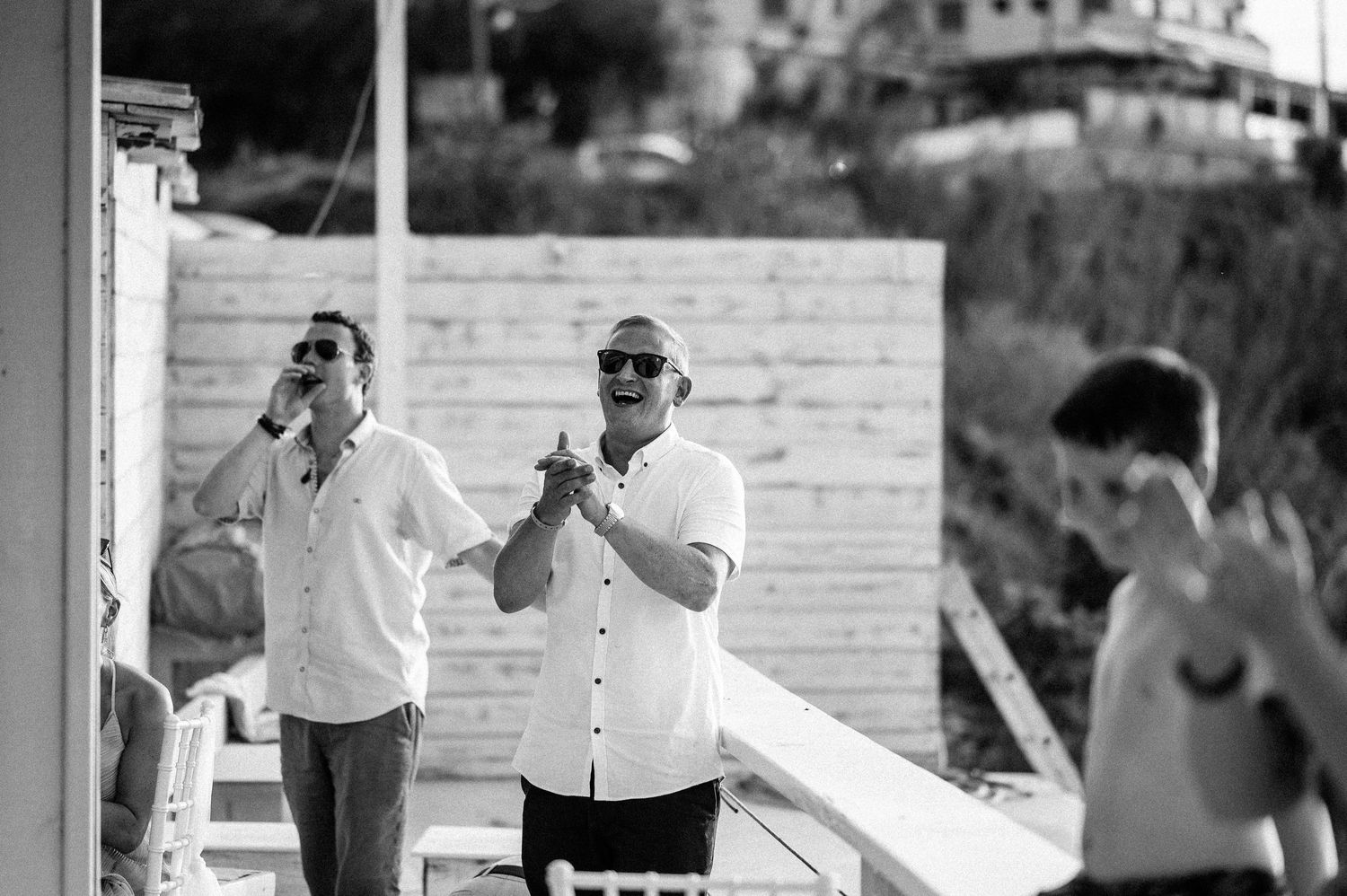 Black and white photo capturing candid moments of wedding guests during reception festivities.