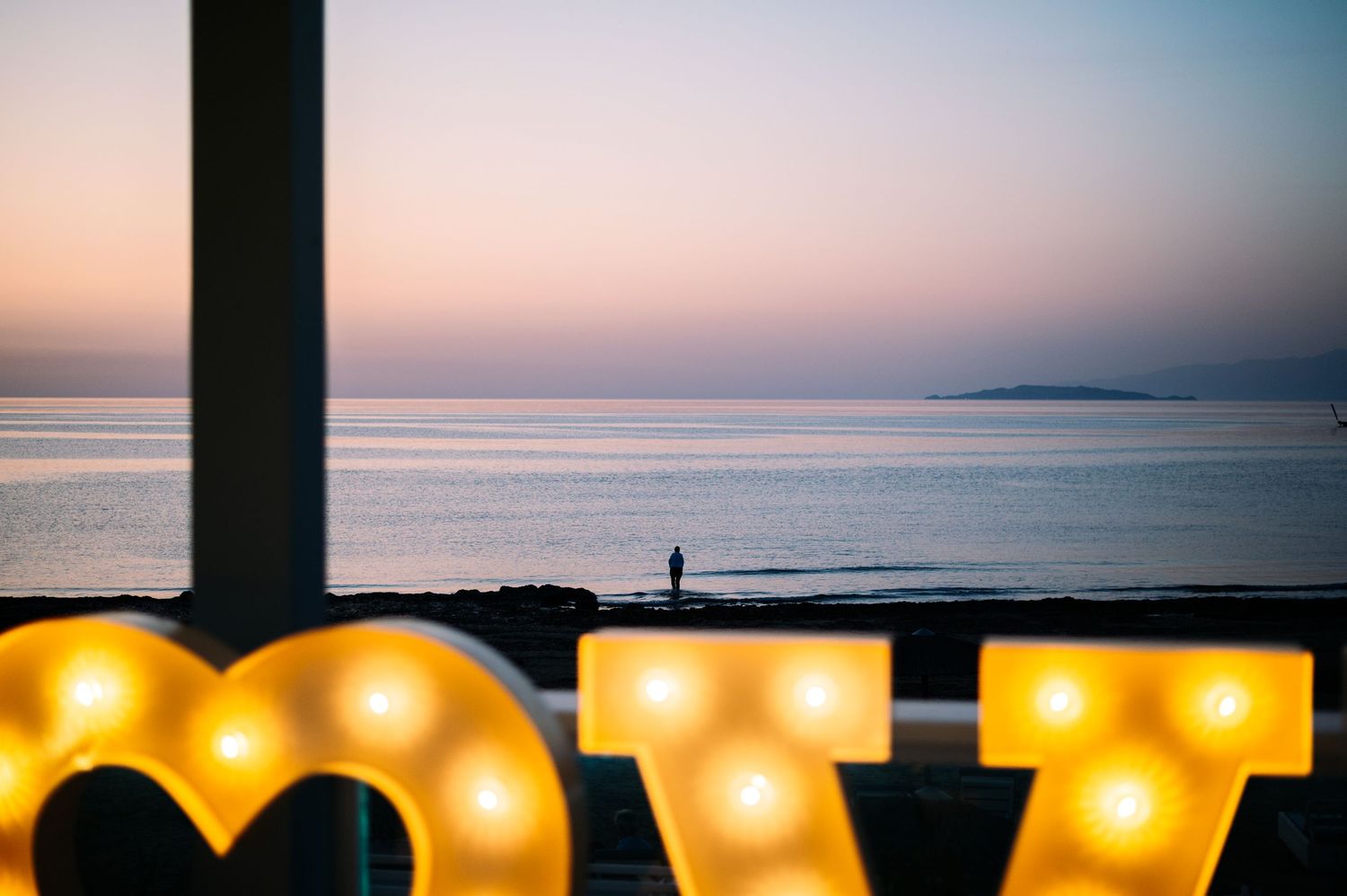 Illuminated LOVE marquee letters glow against a sunset ocean backdrop.
