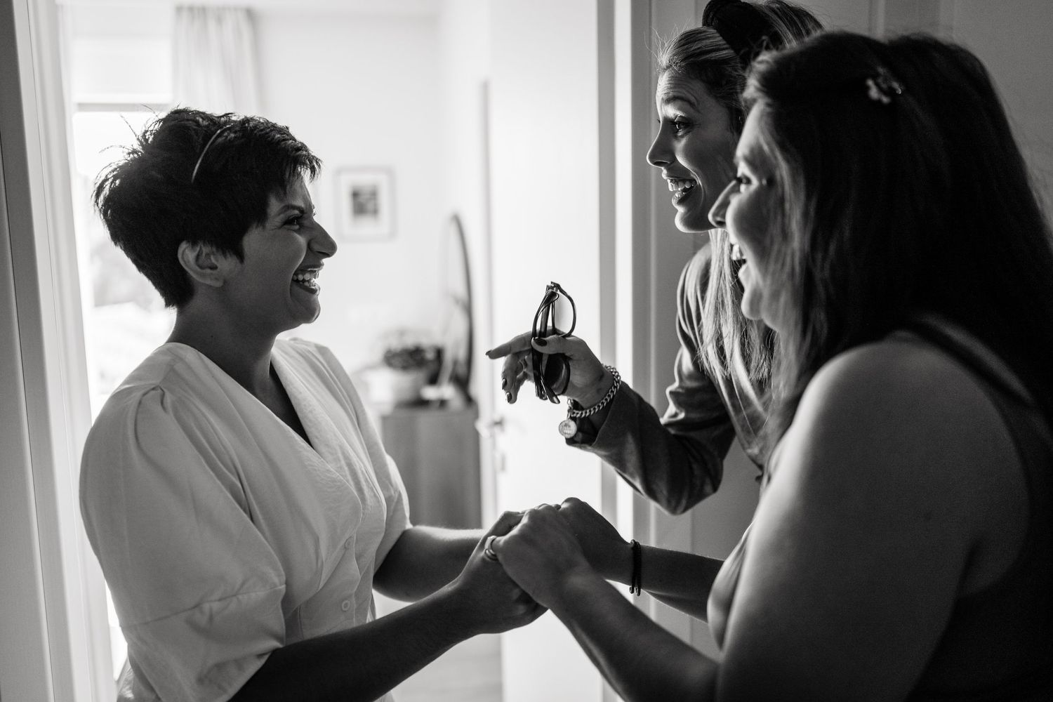 Wedding party getting ready in a bright room with candid black and white moments.
