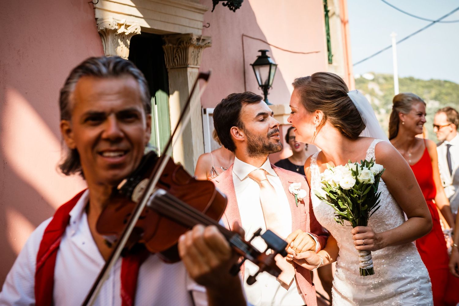 Festive wedding celebration with violin player and guests enjoying outdoor festivities.