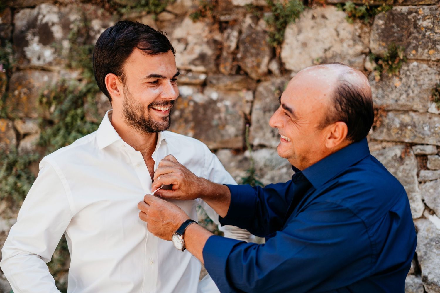 Candid moments of guests celebrating against rustic stone wall backdrop.