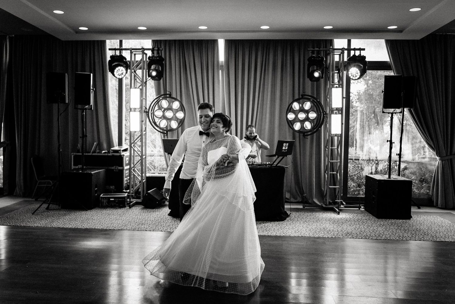 Black and white panoramic view of an elegant wedding reception ballroom with dramatic lighting.