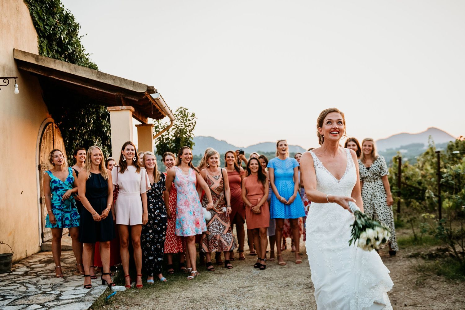 Wedding guests line up against a stone wall with mountains visible in the background.