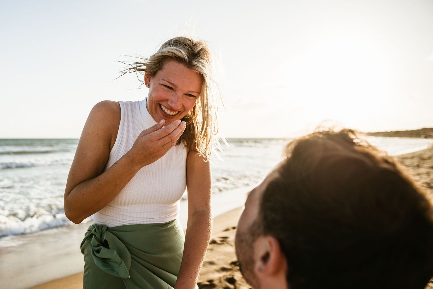 Candid moment of laughter shared between two people on a sunny beach.