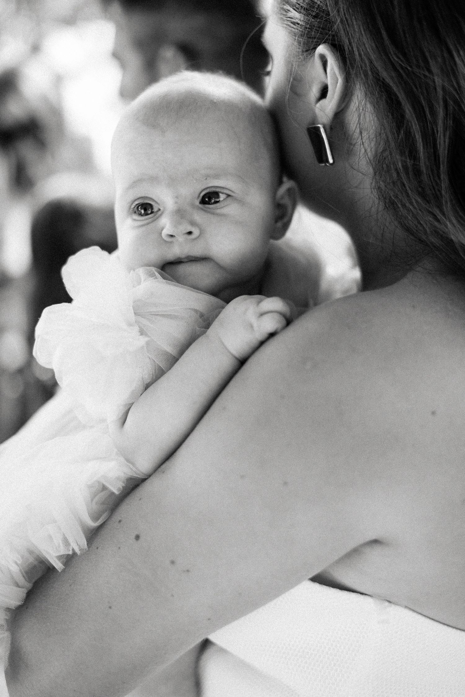 A tender black and white portrait of a baby being held against a shoulder in soft focus.