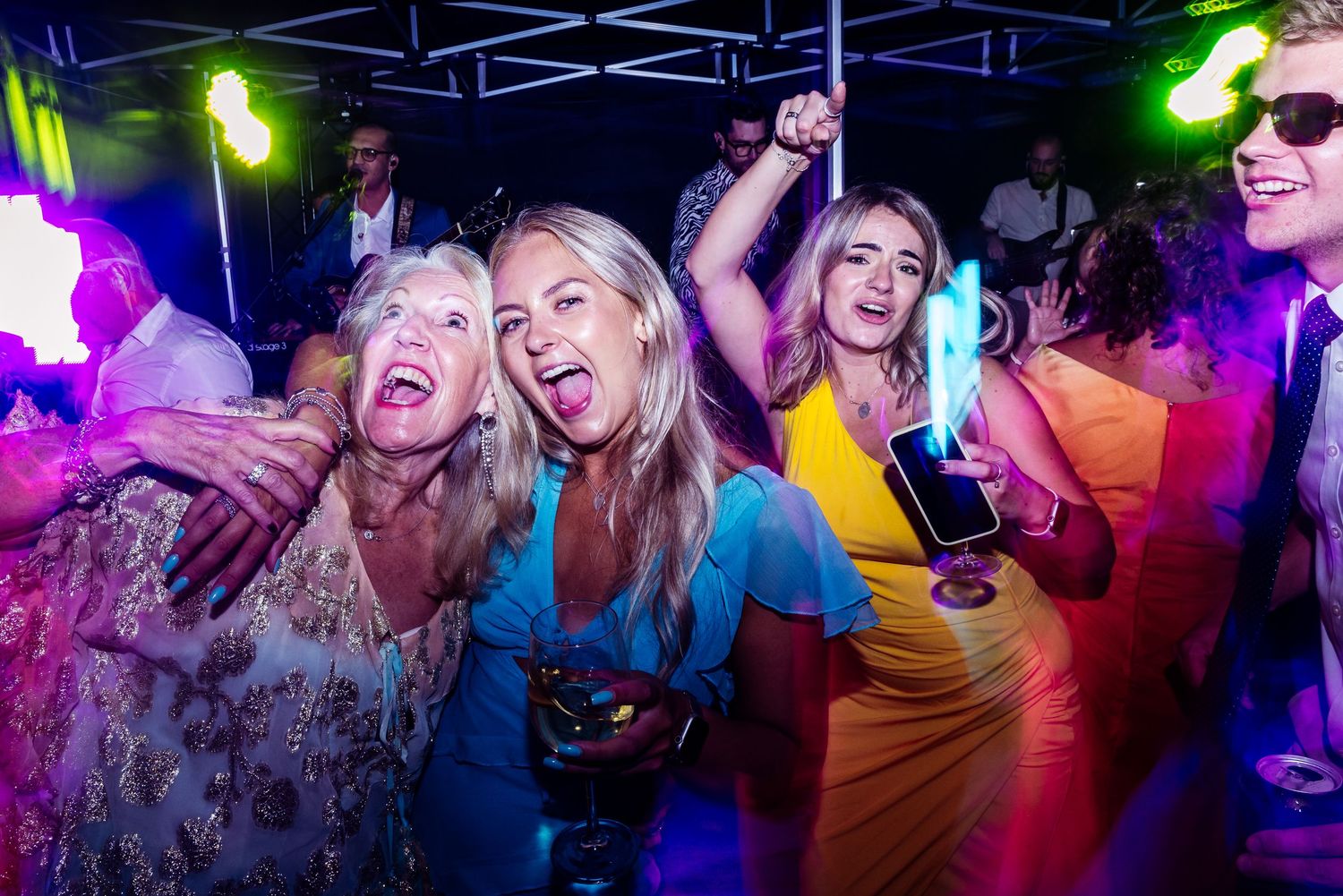 Lively dance party with guests celebrating under colorful disco lights.