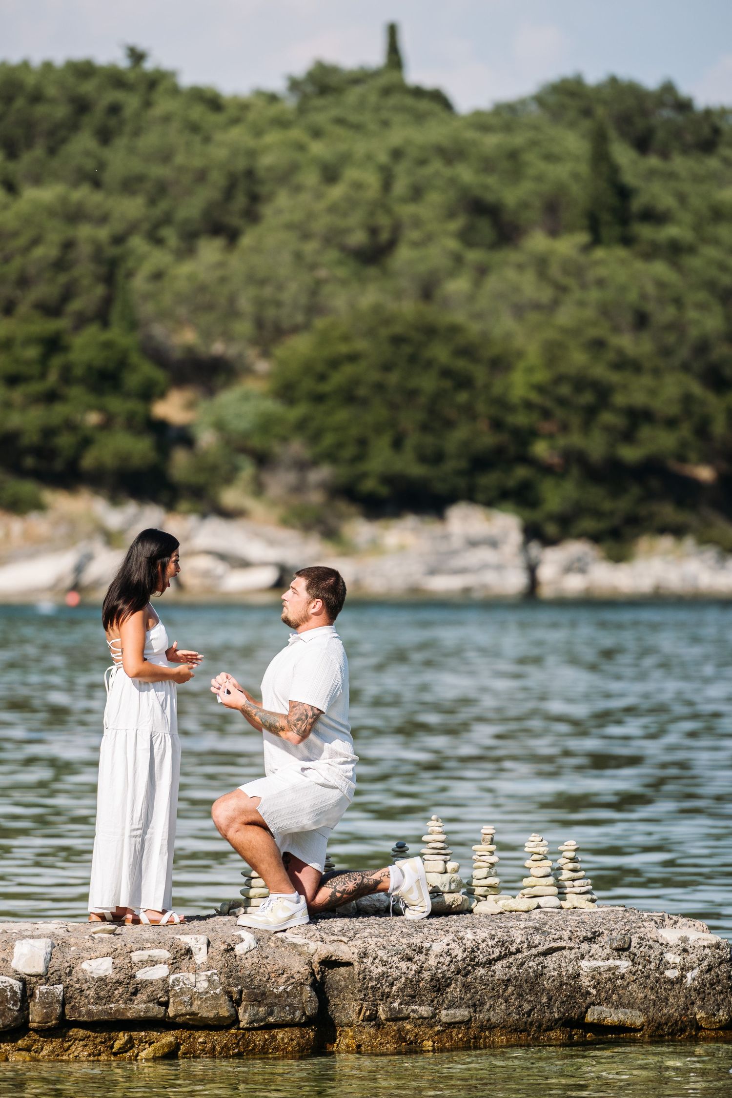 Marriage proposal moment on a rocky outcrop by the sea.
