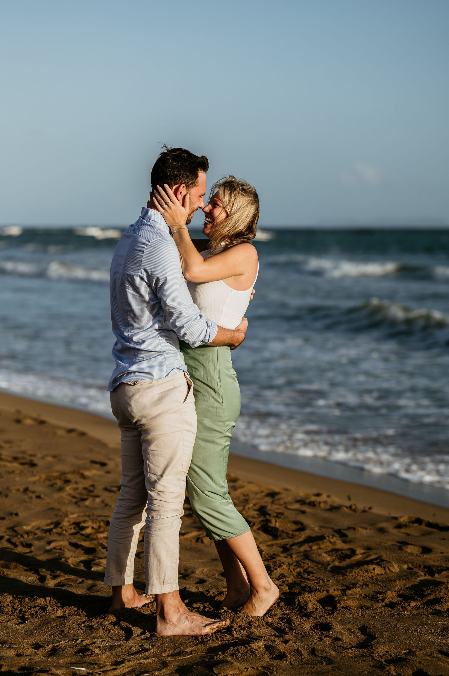 Romantic embrace on a beach with crashing waves in the background.