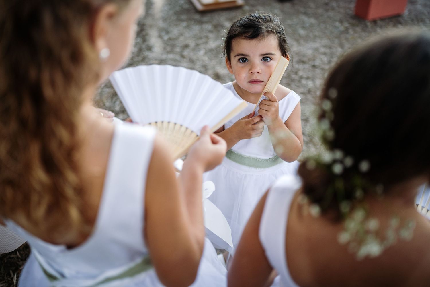 Young flower girls in white dresses prepare for their roles in the wedding ceremony.