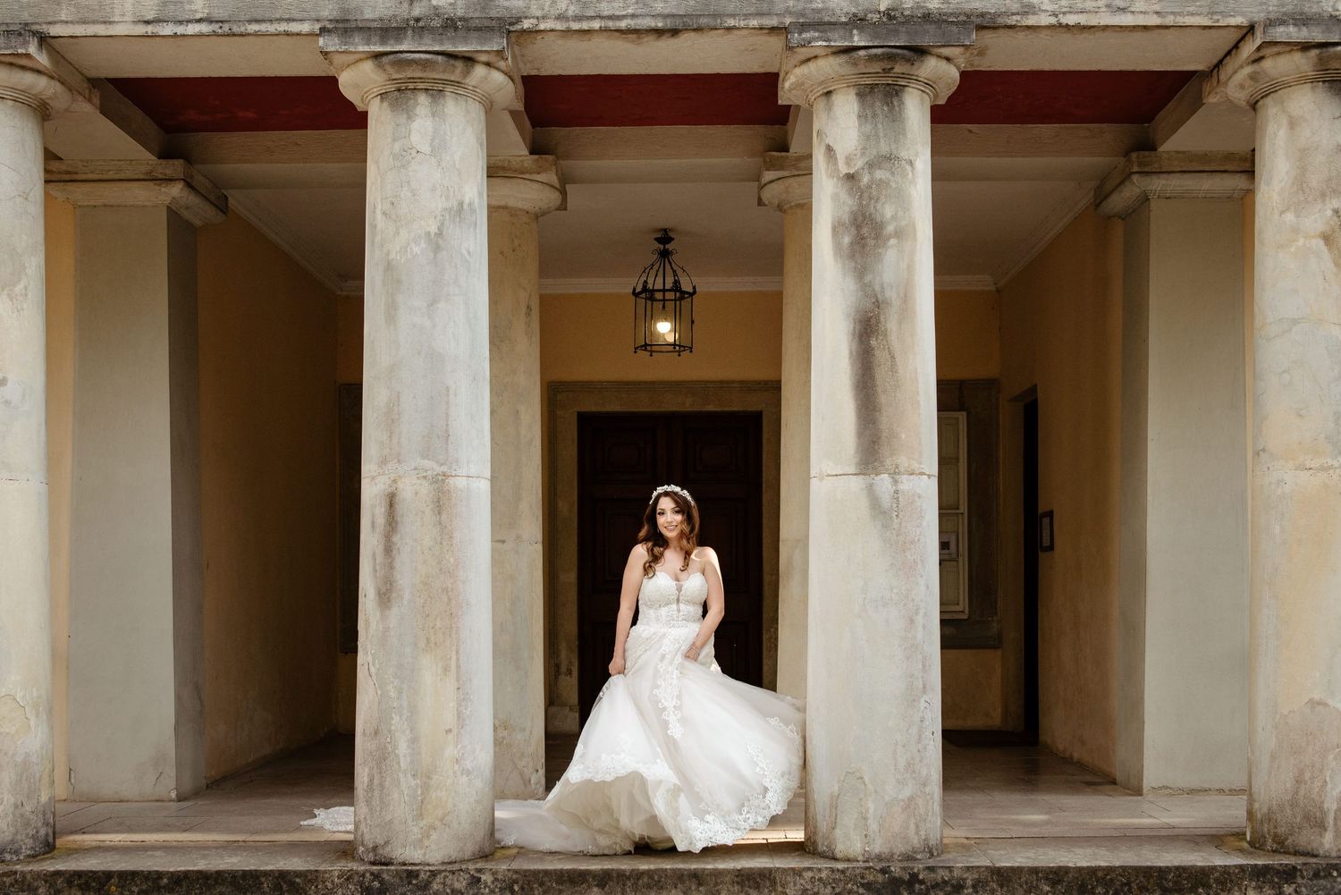 Architectural view of stone colonnade with wedding scene in the distance.